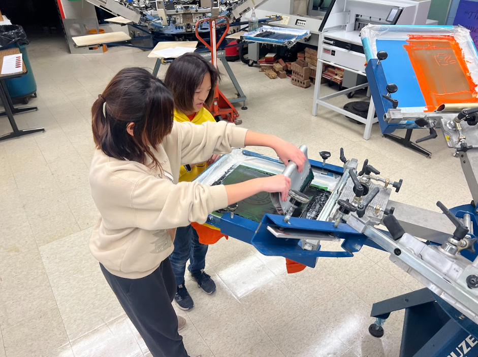 Students press designs onto t-shirts in Brighton High School's Graphics Department.
