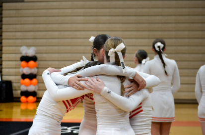 Members of the varsity competition cheer team huddle together at a competition.