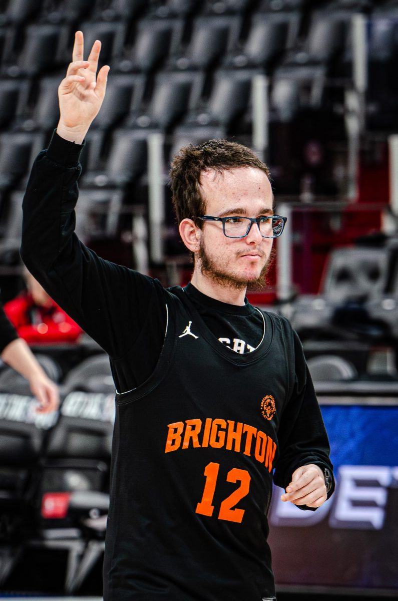 Senior Alexander Skinner waves to his friends at the Little Caesars Arena game to signify that he is open to catching the ball.