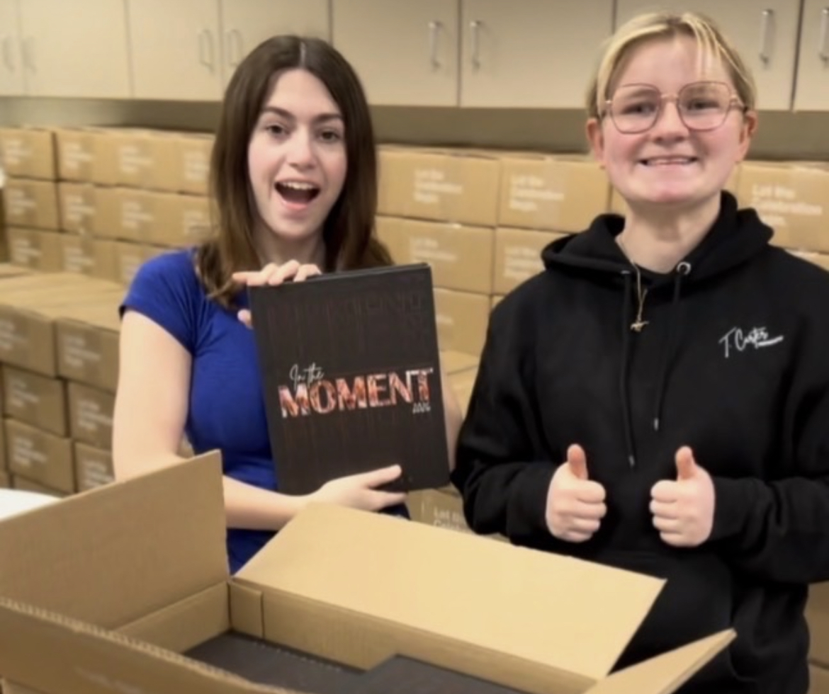 2025-2026 yearbook editors Ari Hickman and Tessa Carter unbox the yearbook.